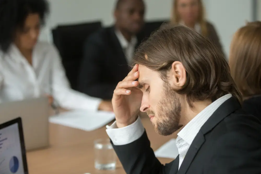 homme qui se tient la tête au travail devant son ordinateur